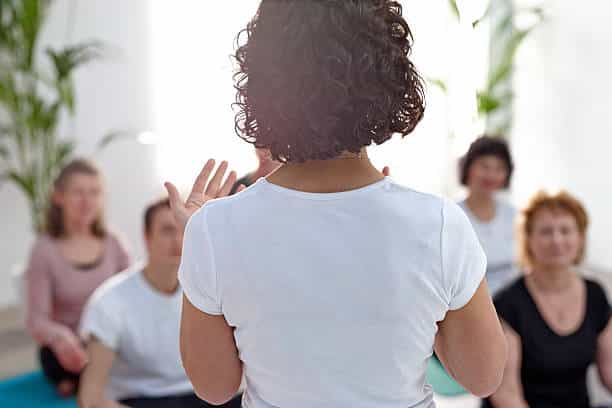 rear view of female instructor guiding student during yoga class